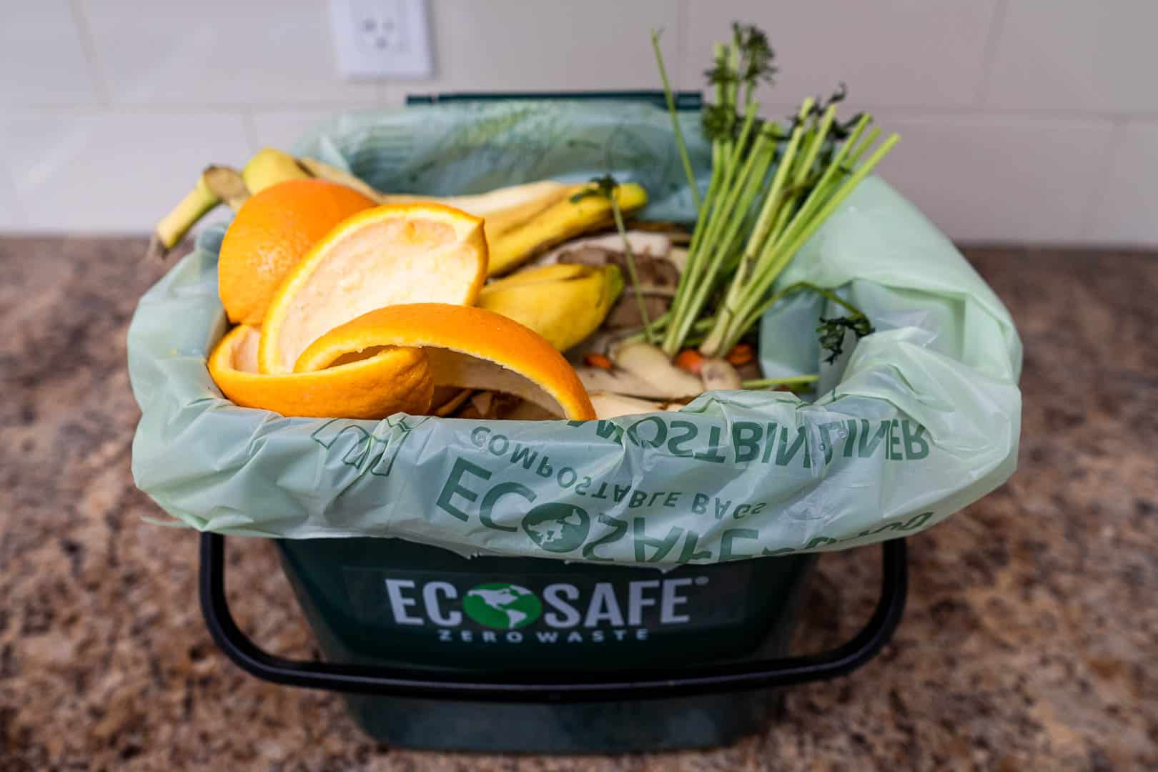 Food waste in compostable bag and bin on kitchen countertop