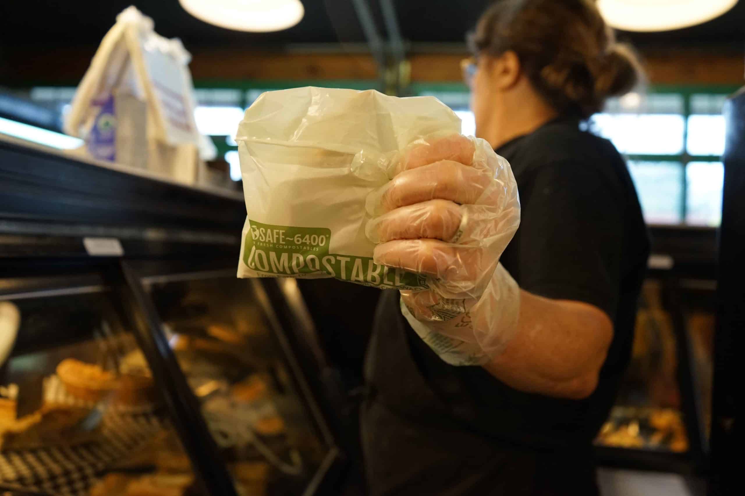 Person at deli holding compostable fold top bag