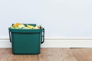 Food waste in a compost bin on a wooden floor