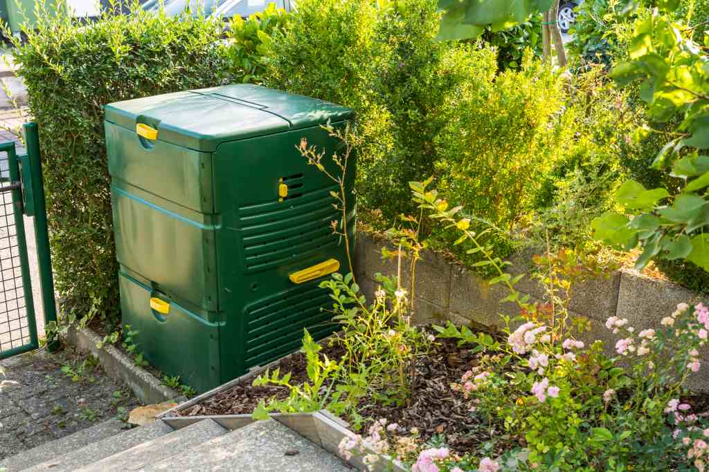 Outdoor compost bin next to hedges